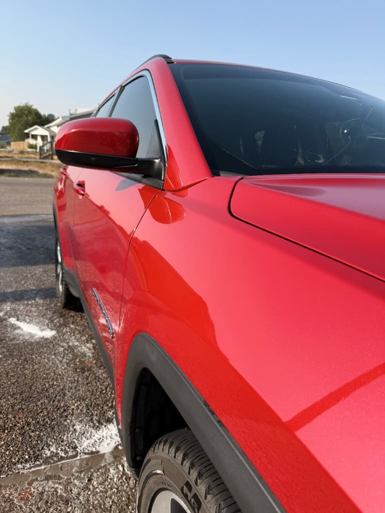 Mirror-gloss red paint along the front fender of a Jeep Compass